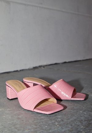 Pink krokodilleprægede sandaler med åben tå-design, firkantet forfod og blokhæl. Glat materiale med en blank finish.