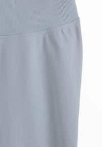 Tissu bleu clair avec une taille côtelée et une couture cousue faisant la transition vers un textile à texture plus lisse en dessous.