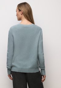 Lyseblå strikket sweater med rund halsudskæring og ribbede manchetter. Blød tekstur med en afslappet pasform, der har en lige kant og en lidt længere ryg.