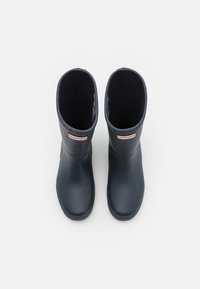 Une paire de bottes de pluie Hunter noires mi-mollet avec doublure en polaire, vue de dessus sur fond blanc.