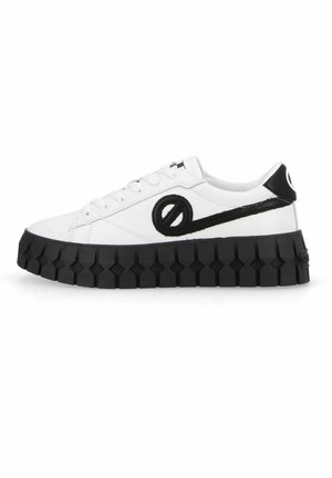 Baskets basses blanches avec une semelle épaisse noire géométrique, un logo circulaire noir brodé et des détails noirs au talon et sur le côté.