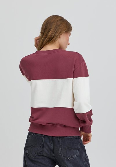 Felpa color block marrone e bianca con maniche lunghe, scollatura rotonda e polsini a costine. Il tessuto sembra morbido con una vestibilità comoda.