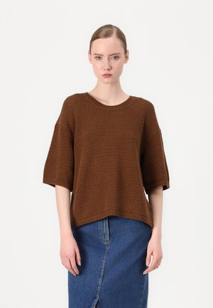 Brown knit sweater with a textured pattern, wide sleeves, and a round neckline, paired with a blue denim skirt featuring a side slit.