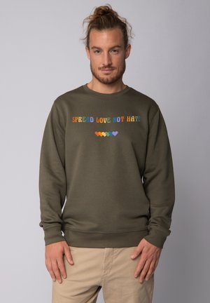 Olivgrüner Sweatshirt mit mehrfarbigem Text "LIEBE VERBREITEN, NICHT HASS" und Herzsymbolen darunter. Hergestellt aus weichem, strukturiertem Stoff.