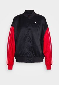Černá saténová bomber bunda s červenými saténovými rukávy, bílými pruhy a logem Jumpman. Žebrované manžety a pas doplňují celkový design.