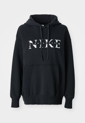 Svart Nike hettegenser med frontlomme, stort logo over brystet, snor i hetta, samt ribbestrikkede mansjetter og kant. Myk bomullsblanding.