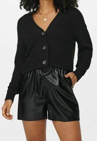 Cardigan en maille noire avec un col en V, doté de quatre boutons et de poignets côtelés, assorti à un short en fausse cuir noir avec un motif texturé.