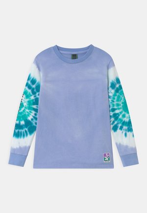 Chemise à manches longues avec corps violet clair et motifs tie-dye tourbillonnants bleu sarcelle et blancs sur les deux manches, avec un petit patch coloré sur l'ourlet.