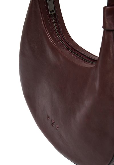 Borsa in pelle borgogna con una silhouette curva, chiusura con zip e logo "VSP" impresso. Texture liscia con una leggera lucentezza.