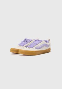 Adidași cu partea superioară crem, accente lavandă și șireturi mov. Talpă din cauciuc cu aderență texturată. Vârf rotunjit și design cu profil jos.