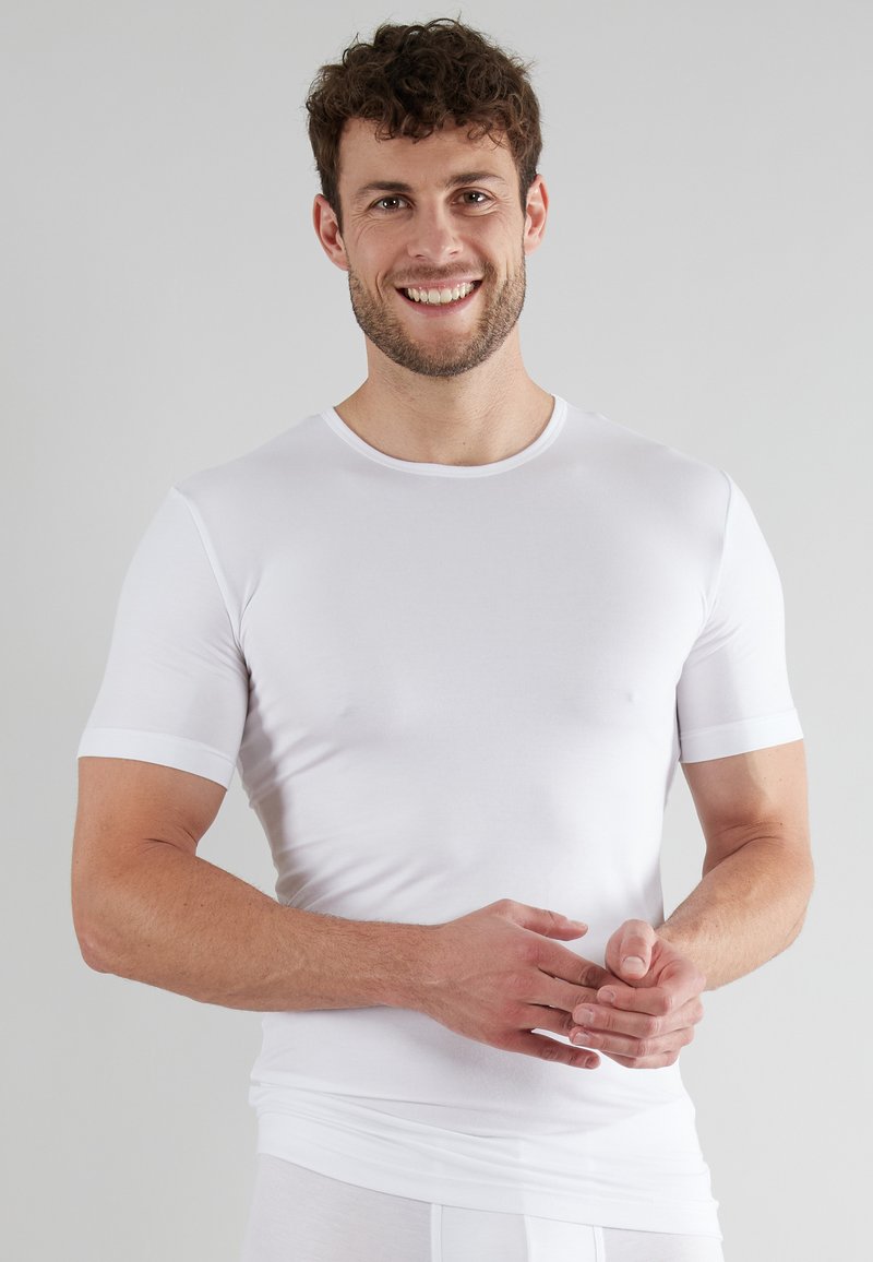 White short-sleeve t-shirt made of stretchable fabric. Fitted design with a rounded neckline and smooth texture, highlighting the body's contours.