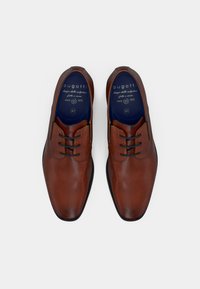 Rjavi usnjeni čevlji za obleko z gladko teksturo, zaobljenim prstom in kontrastnimi temnimi vezalkami. Notranja podloga ima modre poudarke in znamčenje.