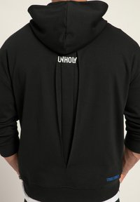 Felpa nera con cappuccio caratterizzata da uno spacco sul retro, con la scritta "UNHOLY" nella parte superiore e un accento blu in basso a destra. Materiale morbido con una vestibilità casual.