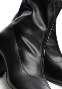 Bottes basses en cuir noir avec orteils arrondis et talons blocs bas, présentées en gros plan sur fond blanc.