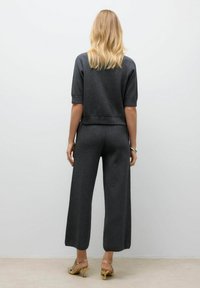 Kolgrå tvådelad outfit bestående av topp med kort ärm och vida byxor, tillverkad av ett mjukt tyg med ribbade detaljer.