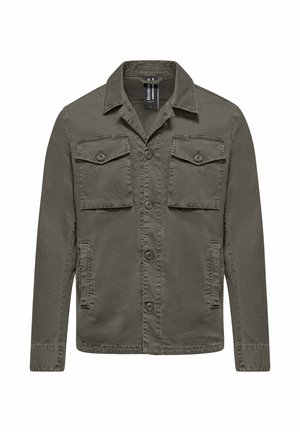 Giacca camicia verde oliva a maniche lunghe con chiusura frontale con bottoni, due tasche sul petto con patta e bottoni, e due tasche laterali.