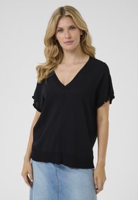 Haut noir à manches courtes avec un col en V, ornée d'une bordure texturée sur les manches et d'une coupe décontractée, associé à une jupe en denim.