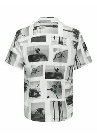 Camicetta a maniche corte in tessuto bianco che presenta un collage di stampe fotografiche in bianco e nero, tra cui scene di surf e palme.
