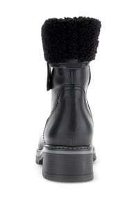 Stivale alla caviglia in pelle nera con risvolto in pelliccia sintetica, punta tonda, tacco robusto e dettagli di cucitura a contrasto. Texture liscia con una finitura opaca.