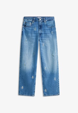Blå jeans med lige ben, en falmet vask og små broderede våbenskjolde spredt ud over forsiden.