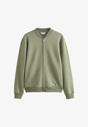 Jachetă verde măslinie cu fermoar, guler rotund, manșete și tiv cu margine ondulată. Textură netedă și design minimalist, fără modele sau accente.