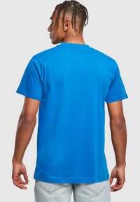Blå bomulds t-shirt med klassisk rund hals, korte ærmer og en afslappet pasform. Glat tekstur og minimalistisk design, set bagfra.