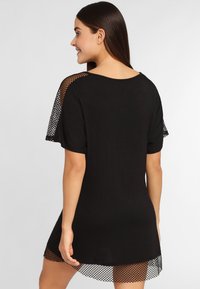 Zwarte jurk met korte mouwen, met een mesh overlay op de mouwen en zoom, biedt een losse pasvorm en een gladde textuur.