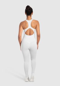 Mono de pierna blanca con diseño de espalda de nadador y detalle de espalda abierta. Fabricado en tejido suave y elástico. Silueta ajustada con costuras mínimas.