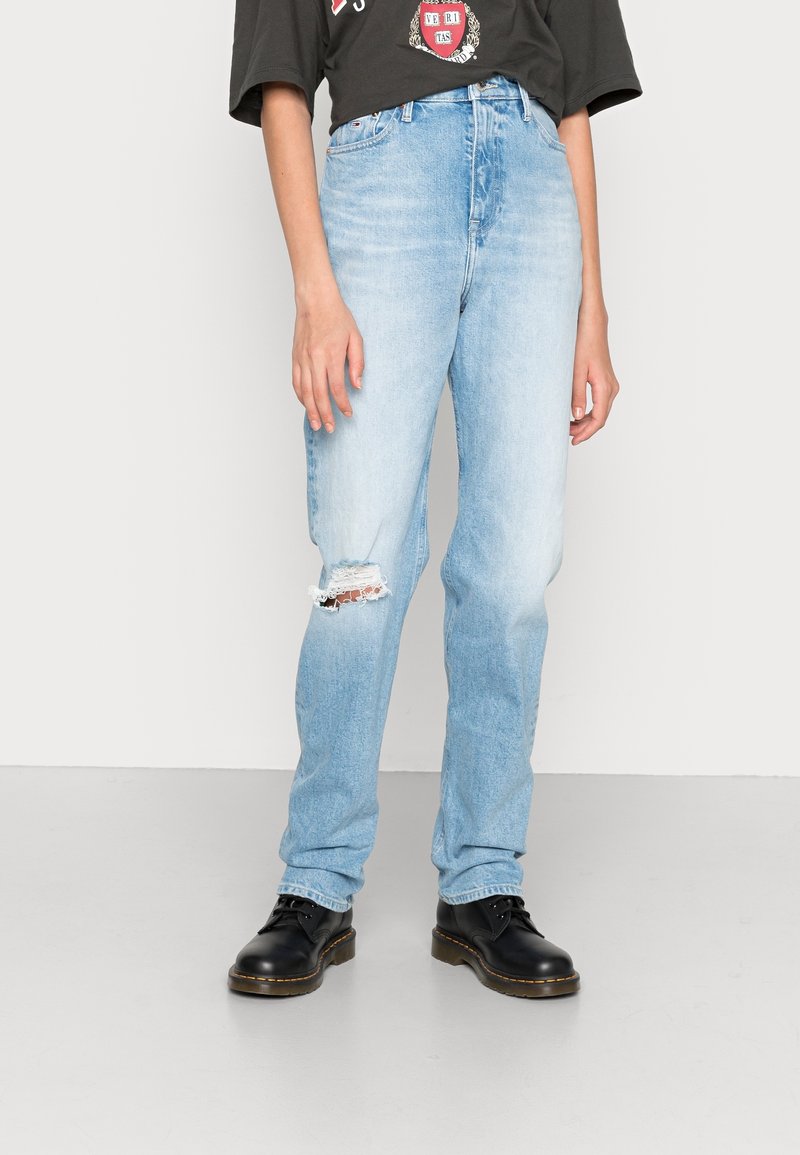 Ljusblå högmidjade jeans med rivna knädetaljer, som bärs med en löspassande svart t-shirt med tryck och svarta snörboots.