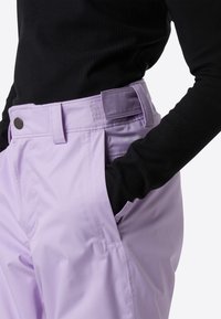 Ανοιχτό μοβ παντελόνι με απαλή υφή, πλαϊνές τσέπες, θηλιές για ζώνη, και μερικώς ορατό μαύρο ριμπ μακρυμάνικο τοπ.