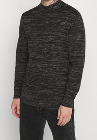Maglione nero a collo alto, con un motivo testurizzato e sottili fili d'argento, realizzato in un morbido tessuto misto.