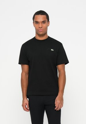 Black cotton t-shirt with a crew neckline, short sleeves, and a subtle green embroidered logo on the left chest. Smooth texture.