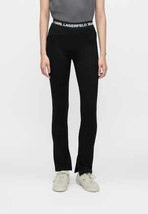 Juodos leggingai, pagaminti iš elastingos medžiagos, su prigludusia forma ir platėjančiomis apačiomis. Turi plačią juosmenį su užrašu "KARL LAGERFELD JEANS".
