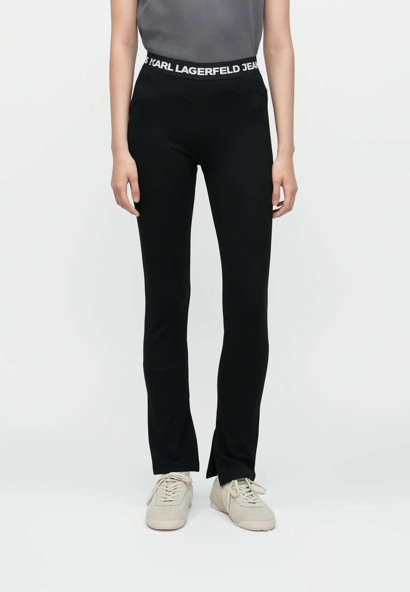 Juodos leggingai, pagaminti iš elastingos medžiagos, su prigludusia forma ir platėjančiomis apačiomis. Turi plačią juosmenį su užrašu "KARL LAGERFELD JEANS".