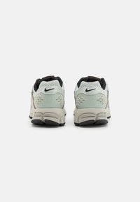 Nike running shoes with a light green mesh upper, diamond-patterned accents, black details, and a cushioned sole with a gray base and black tread.