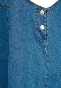 Denim oblačilo v modri barvi s strukturiranim dizajnom; vsebuje dva srebrna gumbka na pritisk in vidno šivanje ob robovih. Mehka tekstura.