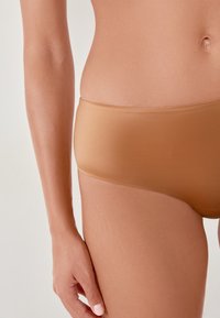 Mutandine hipster seamless color marrone chiaro realizzate in tessuto liscio, con un design minimalista e vita media.