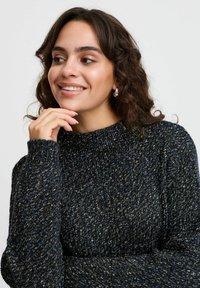 Sweter z dzianiny w ciemnoniebieskim kolorze, z wysokim dekoltem i teksturowanym wzorem z jasniejszymi nitkami. Rękawy o pełnej długości.