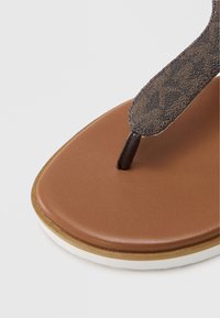 Hnědá syntetická stélka s texturovaným tmavým páskem, s mírným podpatkem a bílým bočním detailem; navrženo pro pohodlí při každodenním nošení.