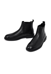 Gli stivali Chelsea neri in pelle presentano una superficie liscia, pannelli laterali elasticizzati con texture a righe, una punta arrotondata e linguette per un'agevole calzata.