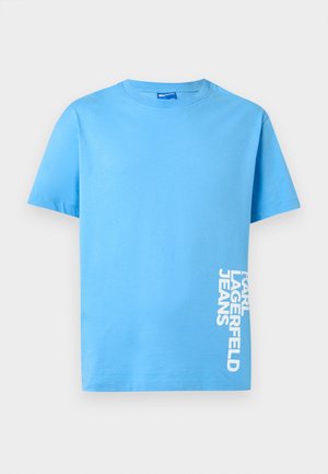 Lys blå kortermet t-skjorte med rund hals og hvit vertikal tekst «Karl Lagerfeld Jeans» på nedre høyre side.