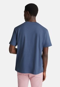 Námořnická modrá trička s krátkým rukávem a klasickým kulatým výstřihem, vyrobené z měkké tkaniny, s hladkým povrchem a uvolněným střihem.