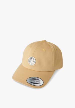 Geltona medvilninė kepurė su apvalia viršūne, išlenktu snapeliu ir reguliuojama diržele. Priekyje yra apskritas logotipo pleistras, šone – etiketė.