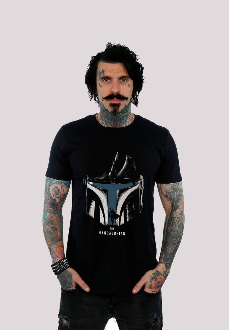 Svart bomull T-skjorte med et grafisk trykk av en Mandalorian hjelm i grått og blått, med teksten "THE MANDALORIAN" under designet.