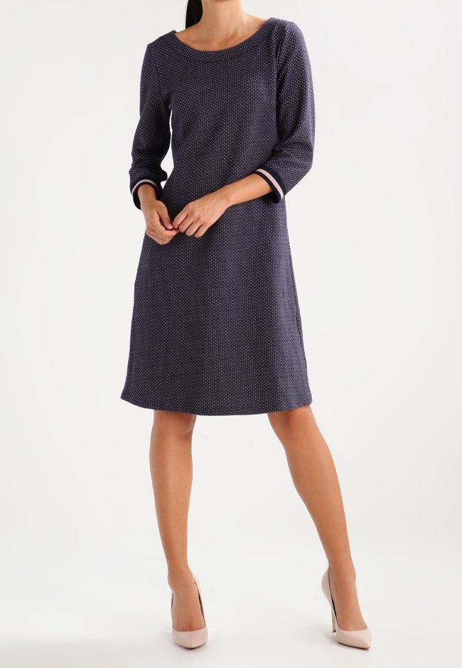 Mörkblå klänning med rund halsringning, trekvart långa ärmar och vitt prickmönster. Slät tyg med kontrasterande ärmuppslag.