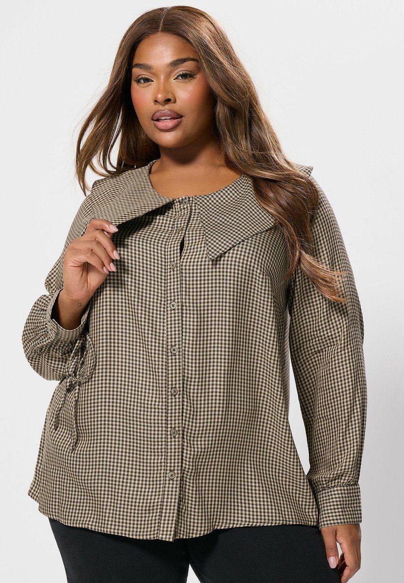 Camicia a quadri marrone e beige con colletto ampio, maniche lunghe e lacci laterali, realizzata in tessuto a fantasia.