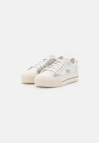 Low-top lace-up sneakers with off-white platform soles and light gray abstract logos on white fabric uppers.
