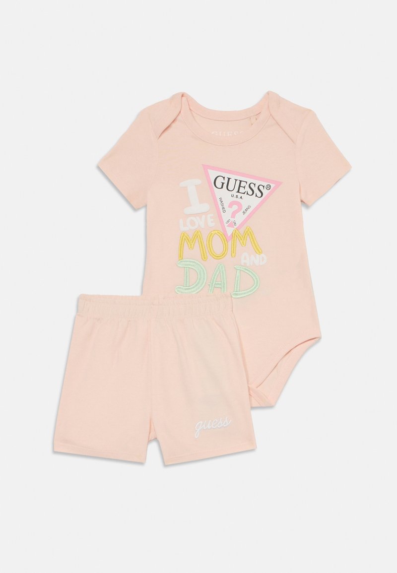 Ljusrosa babyoutfit bestående av en kortärmad bodysuit med färgglad text och matchande shorts med en broderad logga. Mjuk bomullsmaterial.