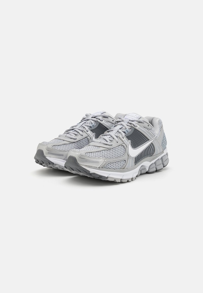 Zapatillas deportivas grises con parte superior de malla y sintético, que cuentan con un swoosh blanco, cierre con cordones y suela texturizada para una mejor tracción.