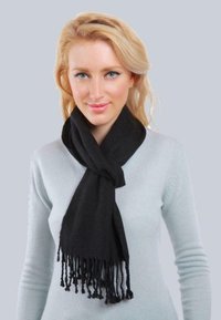 Écharpe noire en tissu doux, avec des extrémités à franges et une coupe drapée, portée sur un pull gris clair.